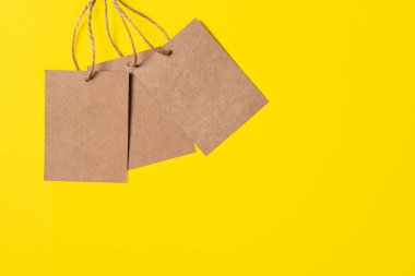 Parlak sarı arkaplanda üç tane el işi kahverengi kağıt etiket var. Asgari stil kopyalama alanı olan satış ya da fiyat afişi.
