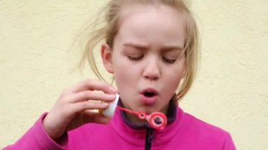 Genç kız sokakta sabun köpüğü üflüyor. Çocuk sokak aktivitesi. 4k çözünürlük videosu