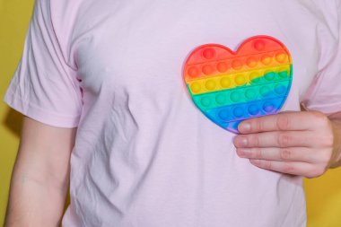 Elinde gökkuşağı kalbi tutan bir adam. LGBT ya da GLBT konsepti. Pop Fidget Duyusal Otizm Oyuncağı Özel Stres Rahatlaması Gerekiyor.