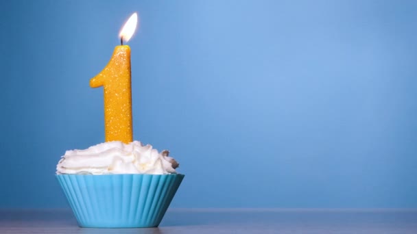 Blow out the candle on the cake. Birthday Cake With Burning Colorful Candle number one on Pastel Blue Background. 120 FPS. Slow motion anniversary banner with copy space — Stock Video