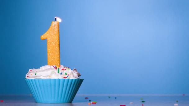 Blås ut ljuset på tårtan. Födelsedag tårta med brinnande färgglada ljus nummer ett på pastell blå bakgrund. 120 FPS. Slow motion jubileum banner med kopieringsutrymme — Stockvideo