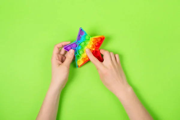 Ruce hrát s Pop It Antistress hra vrtění. Pop Fidget Sensory Toy for Autism Special Needs Stress Relief. Silikonová tlaková hračka v podobě hvězdy pro děti, děti, dospělé. — Stock fotografie