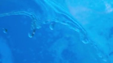 Jakuzide ya da yüzme havuzunda taşan parlak mavi şeffaf su. Video pankartı tam HD çözünürlükte. Dekoratif jet ya da havuzda su şelalesi. Yavaş çekim videosu.