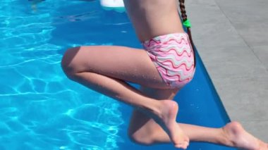 Güneşli bir yaz gününde havuz partisinde havuza atlayıp yüzen mutlu bir kız. Ağır çekim. HD çözünürlük videosu