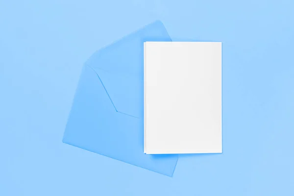 Tarjeta blanca en blanco con sobre azul aislado sobre fondo azul. Plantilla o maqueta. Banner con espacio de copia —  Fotos de Stock