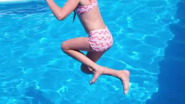 Güneşli bir yaz gününde havuz partisinde havuza atlayıp atlayan mutlu bir kız. Yavaş çekim. HD çözünürlük videosu.