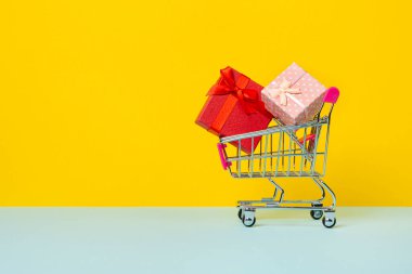 Oyuncak alışveriş arabası ya da hediye kutularıyla dolu bir tramvay. Tatil, yıldönümü ya da doğum günü hediyesi. Sarı arka planda izole edilmiş hediye kutularıyla dolu bir araba.