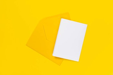 Sarı arkaplanda izole edilmiş sarı zarflı boş beyaz kart. Şablon ya da maket. Kopyalama alanı olan pankart