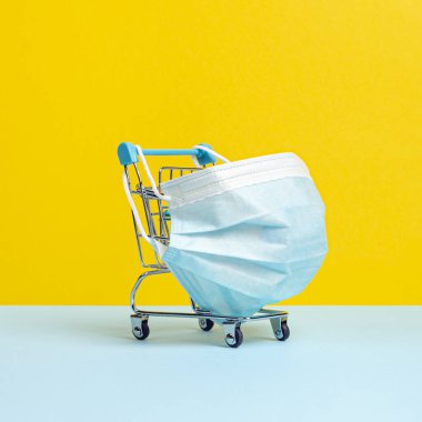 Coronavirus 'a karşı koruyucu tıbbi maskeli alışveriş arabası ya da tramvay. Karantina konseptiyle güvenli ve online alışveriş. Parlak sarı arkaplan