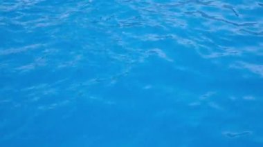Yüzme havuzunda parlak yansımaları olan şeffaf mavi bir su. 4K çözünürlük videosu Yüzme havuzundaki su dokusu