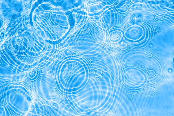 Superficie de la luz azul transparente piscina textura del agua con círculos en el agua. Fondo de naturaleza abstracta de moda. Ondas de agua en banner de luz solar con espacio de copia —  Fotos de Stock