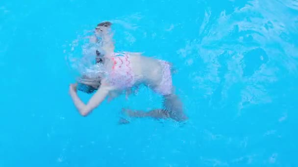 Κορίτσι somersaults και παίζει στο διαφανές μπλε νερό της πισίνας. Το παιδί διασκεδάζει στην πισίνα. Full HD βίντεο αργής κίνησης — Αρχείο Βίντεο