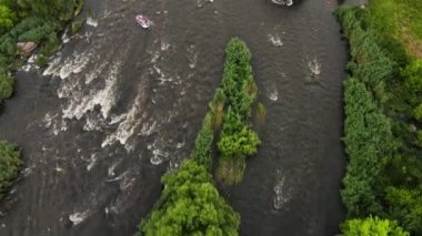 Nehrin güzel manzaralı insansız hava aracı. Akıntılı, şelaleli ve ekstrem rafting yapan. Bir grup insan botla nehirde rafting yapıyor.