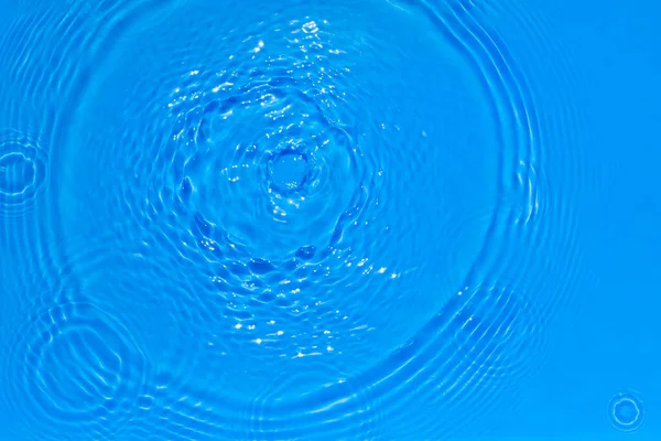 Surface of bright blue transparent swimming pool water texture with circles on the water. Trendy abstract nature background. Water waves in sun light reflections. — Stock Photo, Image