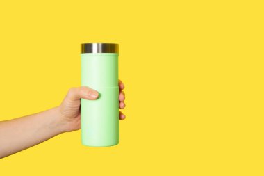 Beyaz arka planda açık sarı seyahat kupası var. Kadın elinde termo bardak ya da bardak. Kopyalama alanı olan pankart.