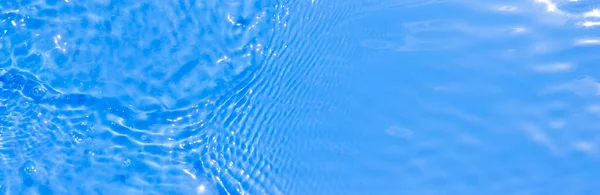 물 위에 반사되는 빛 과 함께 청색의 투명 한 수 영장의 수면 질감. 유행하는 추상적 인 배경. 태양 광선의 파도는 반사된다. 복사 공간 이 있는 긴 깃발. — 스톡 사진
