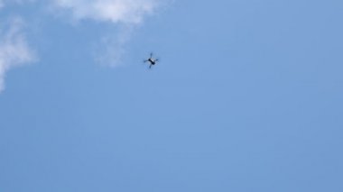 Helikopter tepeden tırnağa uçuyor. Uçan İHA 'nın, helikopterin ve mavi gökyüzünün dibinde. Yukarıdan fotoğraf ve video çekmek için modern teknolojiler. Kameralı bir kuadkopter.