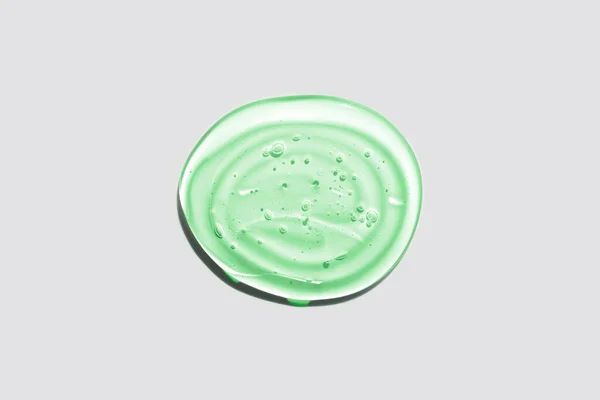 白色の背景に緑色の透明な丸ジェルドロップを分離。最上階だ。ウイルス保護や化粧品の概念。顔の血清の質感を閉じます. — ストック写真