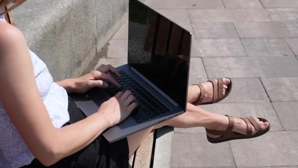 Una joven mujer o niña que trabaja en un portátil en un banco en el parque. Concepto independiente, educativo o de trabajo en línea. Vídeo de resolución 4k — Vídeo de stock