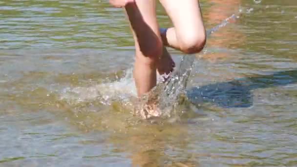 ビーチで浅い水の中でぬれた砂の上を走る遊び心のある子供の足のビューを閉じて、肯定的な感情を感じてください。フルHDスローモーションビデオ.夏休みのコンセプト — ストック動画