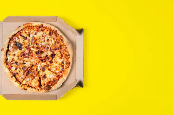 Tasty hawaii pizza in a box isolated on yellow Top view on paperoni pizza. Concept for italian food, street food, fast food, quick bite. Food banner with copy space