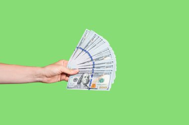 Yeşil arka planda izole edilmiş bir yığın banknotla el ele tutuşuyoruz. Zenginlik ya da kredi konsepti. Kopyalama alanı olan pankart
