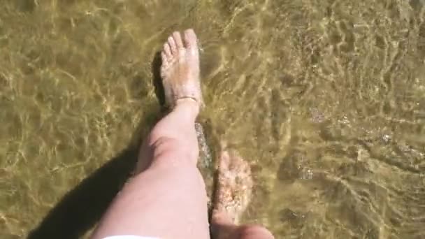 Vue rapprochée sur les jambes de marche mâles adultes sur une belle plage avec des reflets d'eau. White Mans pieds marchant sur la plage. — Video