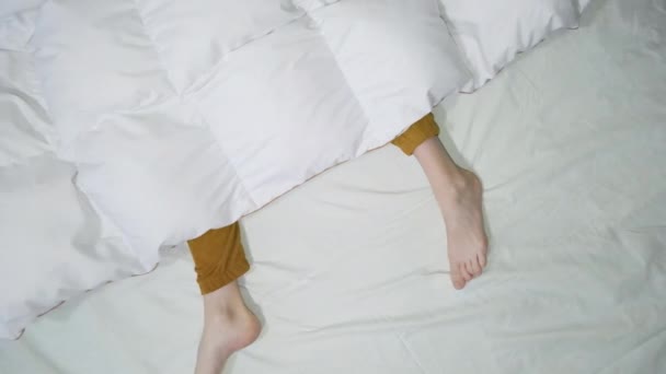 Dron pohled na ženské nohy v oranžové pyžamové kalhoty pod bílou přikrývkou — Stock video