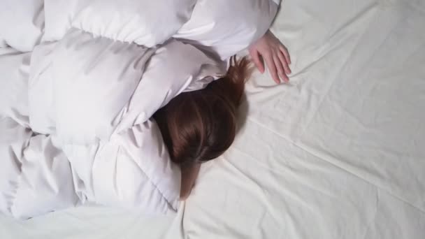 Uyuyan kız ya da kadın için drone görüşü. Battaniyenin altında yatakta dönüp duran ve uyumaya çalışan birinin üst hava görüntüsünü kapat.. — Stok video
