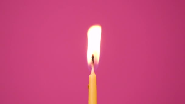 Σβήνω το κερί που καίει σε ροζ φόντο. Κοντινό πλάνο με το φύσημα από κίτρινο κερί κέικ. Πλήρης ανάλυση HD αργή κίνηση Χρόνια πολλά ή επέτειο βίντεο — Αρχείο Βίντεο