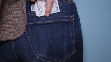 Kadın ya pantolonunun arka cebine para koyar ya da saklar. Kotun cebine para koyuyor. Para kazanma, rüşvet, kara para kavramı.