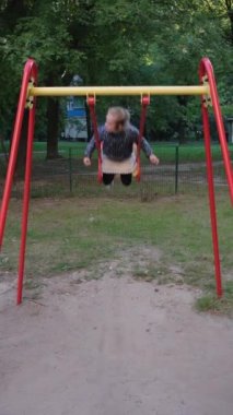 Mutlu ve gülümseyen genç kız salıncağa biniyor. Kız parkta salıncakta sallanırken eğleniyor. Boş zaman aktivitesi ve çocukluk konsepti. Tam HD yavaş çekim videosu