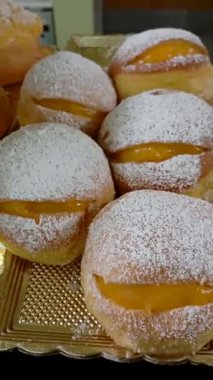 Altın tepside pudra şekerle kaplanmış taze kremalı çörekleri yakından çek. Tatlı, fırın, tatlı yemek ve ev yapımı hamur işi kavramı.