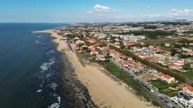 Espinho, Portekiz - 12.10.2025: Portekiz 'in Espinho kıyı kasabasında uçan hava aracı videosu, güzel plajlar, okyanus dalgaları ve kırmızı çatılı evleri gösteriyor.