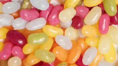 Renkli küçük jöle şekerler rastgele hareket ediyor. - Evet. Kusursuz döngü. Şekerler, tatlılar, çocuk ürünleri, yemek reklamları ve şenlik havası için neşeli ve hayat dolu bir geçmiş.