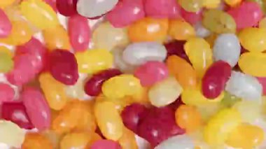 Renkli küçük jöle şekerler rastgele hareket ediyor. - Evet. Kusursuz döngü. Şekerler, tatlılar, çocuk ürünleri, yemek reklamları ve şenlik havası için neşeli ve hayat dolu bir geçmiş.