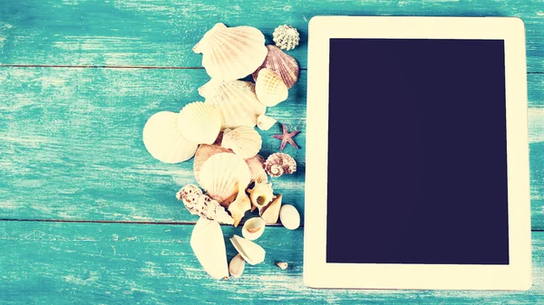 Tablet, deniz kabuklarını, mavi ahşap arka plan