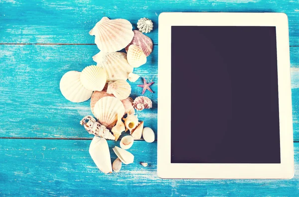 Tablet, seashells, blue wood background — Stock Photo, Image