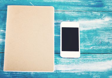 dizüstü bilgisayar ve cep telefonu eski mavi ahşap kurullarında.