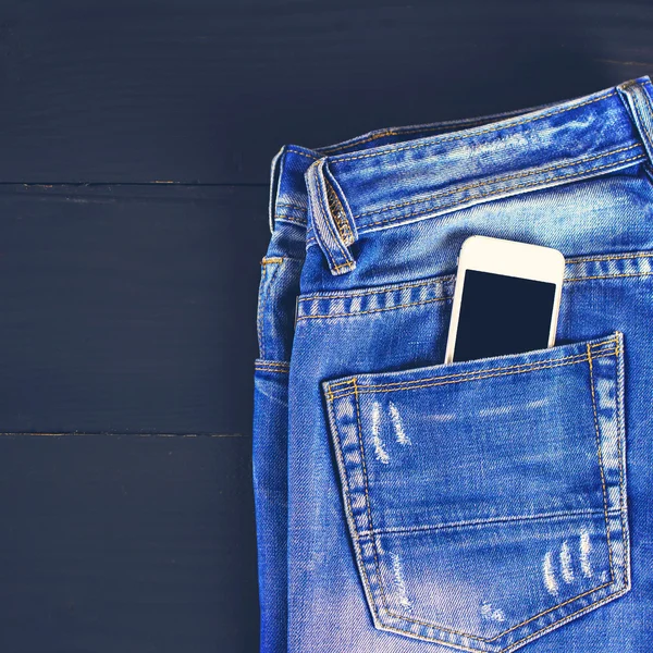 jeans and mobile phone on wooden boards.