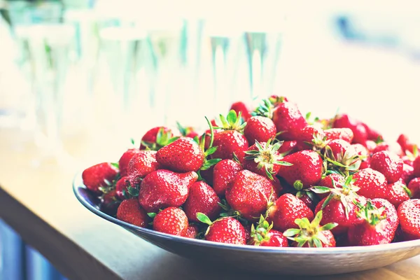 Schotel met aardbeien en champagne glazen op tafel. — Stockfoto