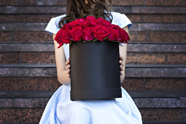 Mooi meisje met boeket van rode rozen — Stockfoto