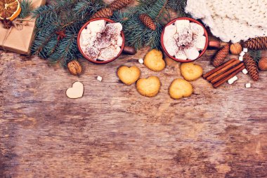 Kakao, kahve, hediye, köknar dalı, fındık, koni, sıcak örgü battaniye. Noel kurabiyeleri Bir kadının eli bardağı tutar.