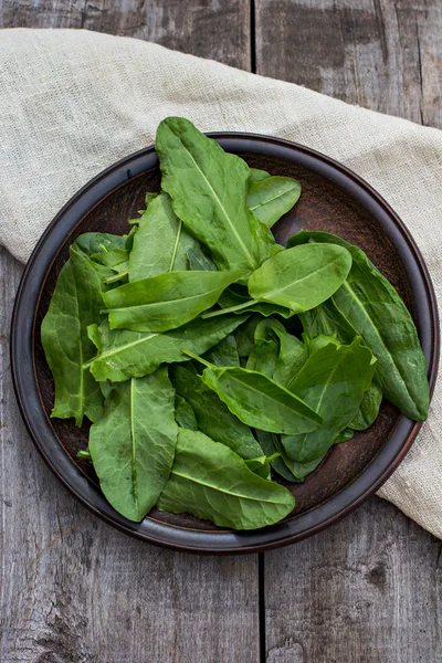 Sorrel leaves on a plate, the plate is on the old boards — Stock Photo, Image