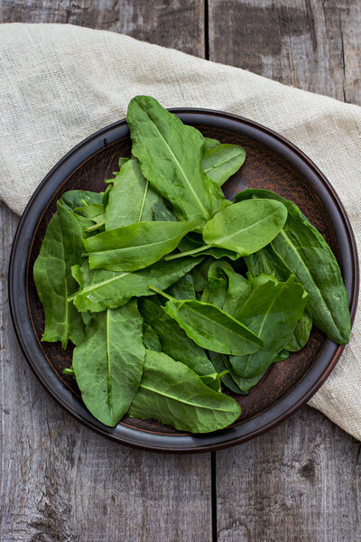Sorrel leaves on a plate, the plate is on the old boards