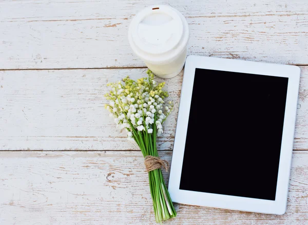 Tablet bilgisayar, bir bardak kahve ve lilyum masada Vadisi