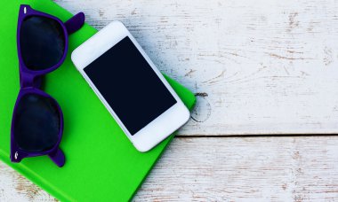 Dizüstü bilgisayar, cep telefonu ve ahşap bir masa üzerinde güneş gözlüğü