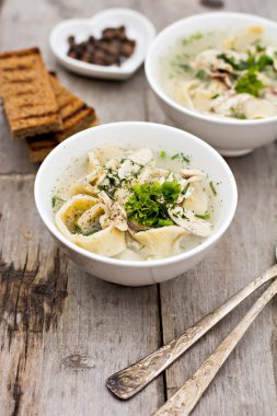 Bir kase erişte ve ahşap bir masa üzerinde tavuk çorbası