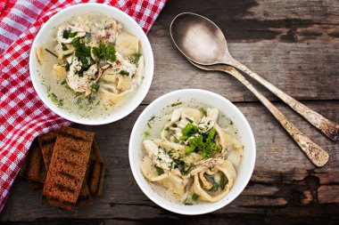 Bir kase erişte ve ahşap bir masa üzerinde tavuk çorbası