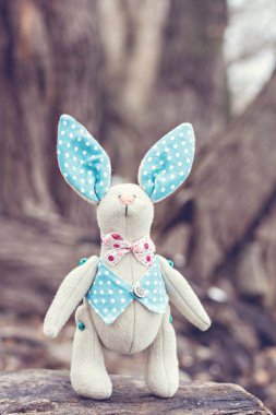 Yumuşak oyuncak - bunny eski bir ağaçta oturuyor.